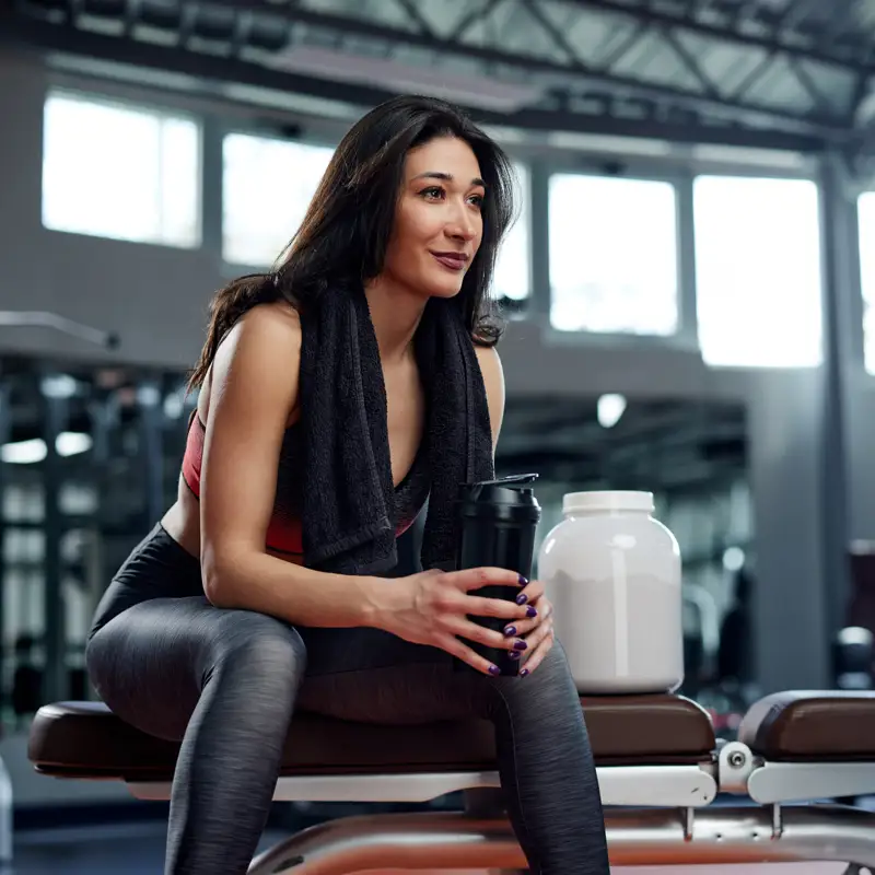 Chica en el gimnasio con batido de proteínas