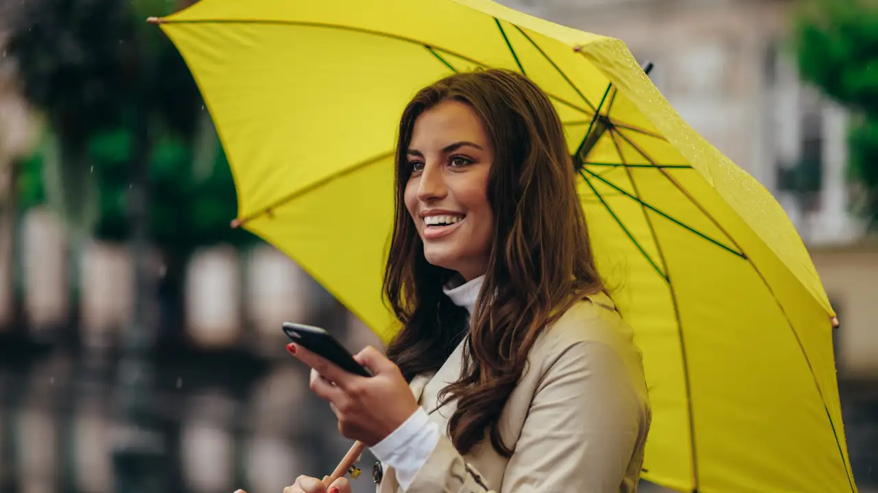 Mujer comprando con el móvil bajo la lluvia