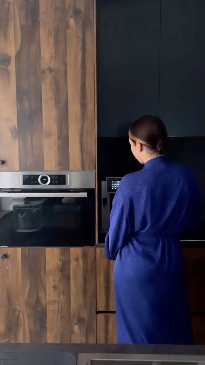 Una cocina con muebles negros y en madera oscura