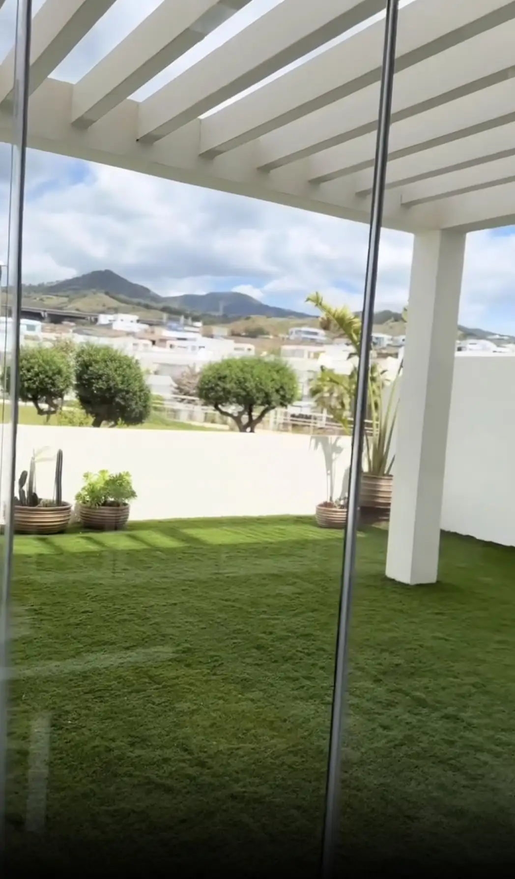 Césped artificial y plantas naturales y una pérgola de madera